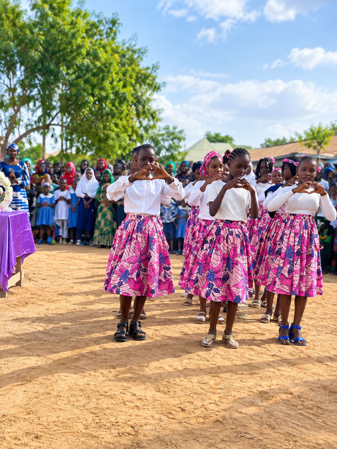 Greater Future Academy pupils in matching outfits performing a heart-hands dance for a crowd at a school celebration